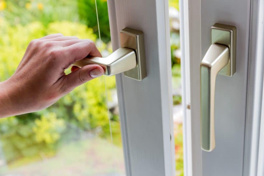 Hand öffnet ein Fenster zum Lüften gegen Radon