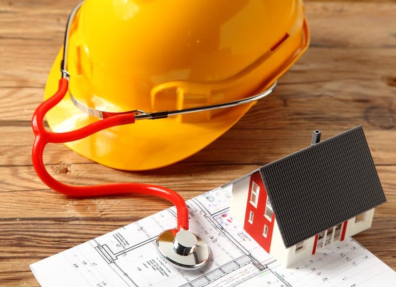 Bauhelm, Stethoskop und Hausmodell als Symbol für die Radon-Gebäudeanalyse